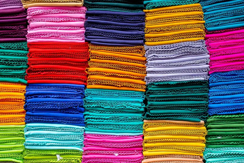 Neat stacks of folded cloth in red, orange, blue, teal, pink, yellow and green packed side by side